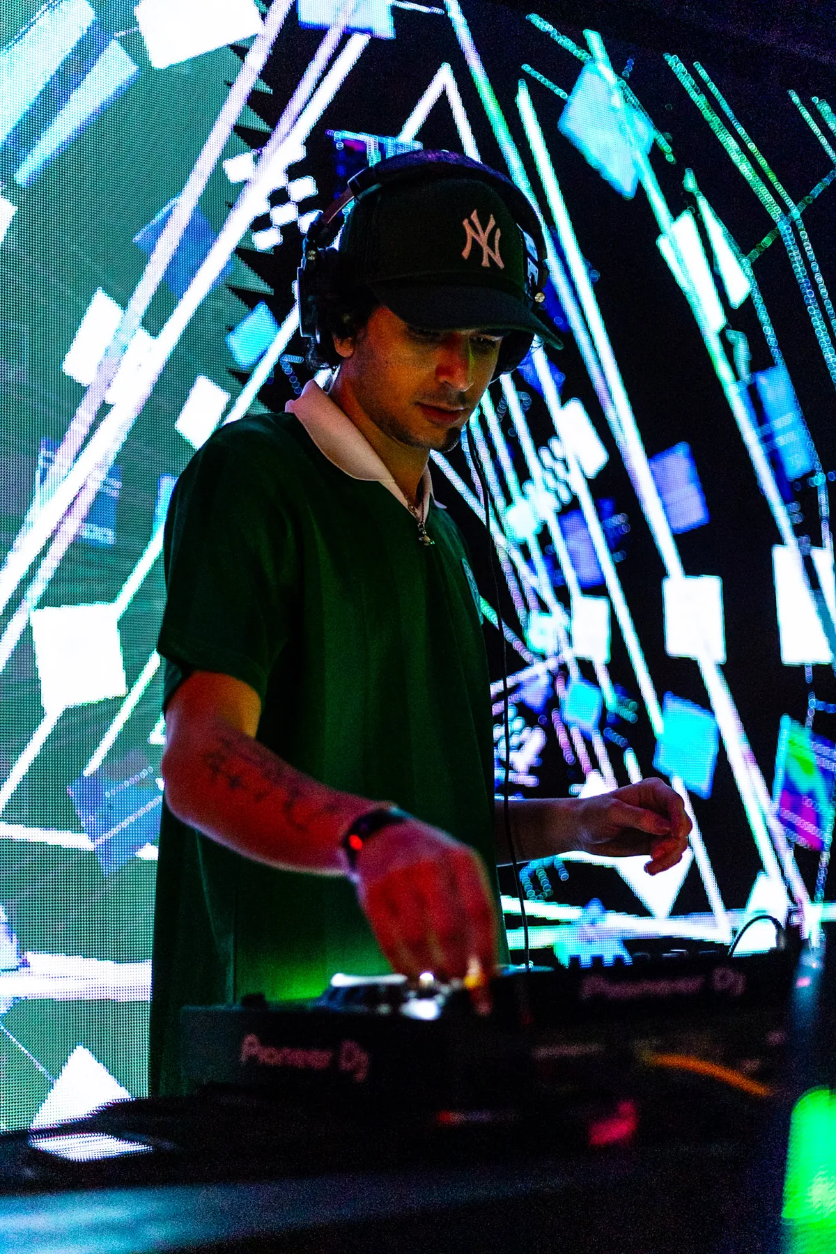 babyjah performing behind a DJ mixer against bright LED visuals